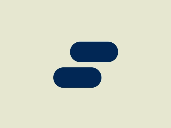 The Skedulo logo features two dark blue, pill-shaped forms, one positioned vertically above the other, aligned centrally on a horizontal axis. The shapes are uniform in size, showing a minimalist design with a clean, modern aesthetic. The deep blue gives a sense of professionalism and reliability, while the simplicity of the forms suggests accessibility and ease of recognition. The shapes are devoid of additional embellishment, which contributes to the logo’s versatile and timeless appearance.