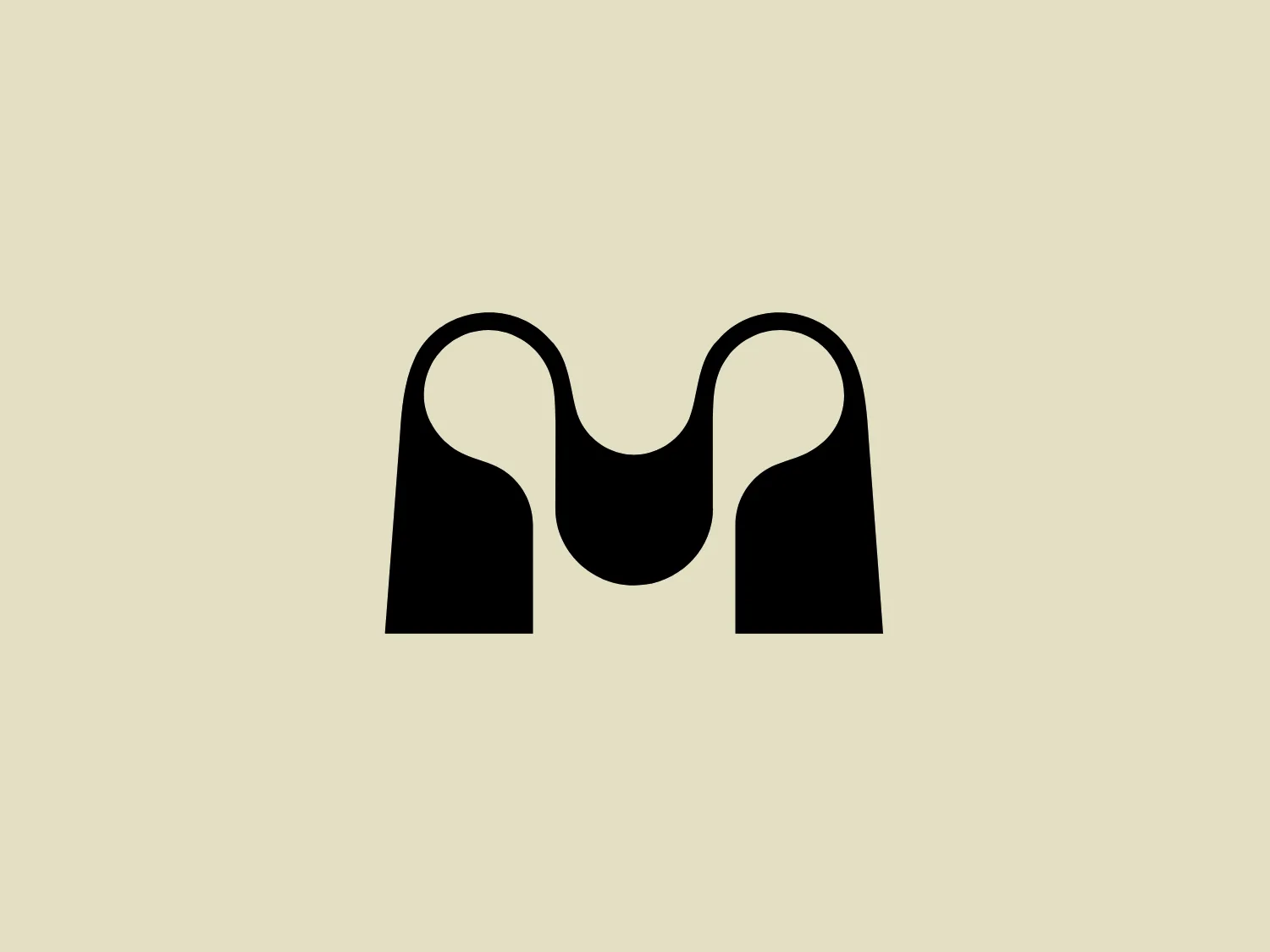 The Atelier Majuscule logo is a minimalistic and symmetrical design featuring two black shapes resembling abstracted letter Ms or mountain peaks with a smooth, wavy connection between them. The design is sleek, with the use of negative space creating the illusion of a continuous, flowing line. The shapes are bold and filled with a solid black, giving the logo a strong and modern presence. The simplicity of the design allows for versatility in various applications.