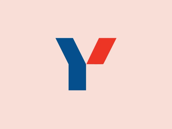 The image displays a stylized, geometric logo composed of two distinct shapes forming a letter 'Y' for the business Yazbek. The left arm of the 'Y' is a deep blue color with a vertical orientation, while the right arm extends out diagonally in a bold red color. The shapes converge seamlessly to form the clean, angular letter, suggesting a merge of two entities or a dynamic directional movement. The overall design is minimalist and modern, with a strong contrast between the blue and red elements, and no additional embellishments. This crisp design conveys a sense of innovation and professionalism.