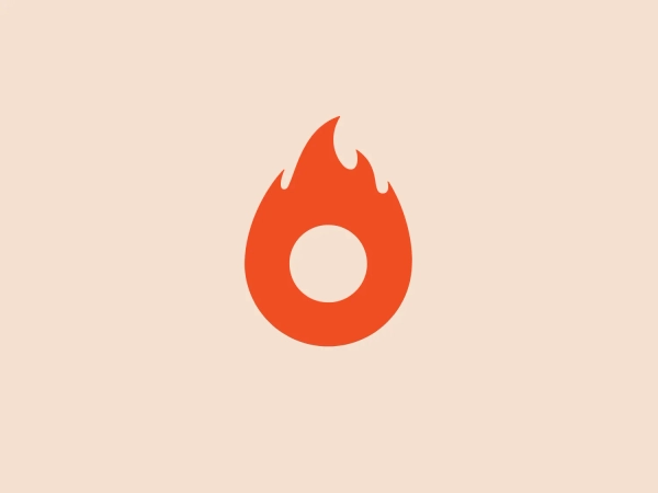 The logo features a stylized flame with a modern, minimalist design. The main body of the flame is a bright, solid red-orange color, evocative of heat and energy. The flame has smooth, curved lines creating the iconic teardrop shape of a fire motif, with pointed tips at the top that suggest a flickering movement. Within the flame silhouette is a white, circular cutout at the center, providing an effective contrast and drawing the eye to the middle of the design. This negative space could be interpreted as the source of the flame or an eye, adding a layer of symbolism to the logo.