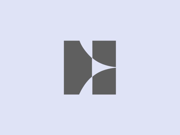 The Harmon logo is a minimalist, modern design featuring two interlocking shapes: a square on the left and a stylized letter 'N' on the right. Both shapes share a soft curve where they meet, creating a sense of unity and fluidity. The logo employs a monochromatic color scheme with different shades of muted blue or gray, giving it a professional and sleek look. The clean lines and the absence of additional embellishments or text suggest a focus on modernity and simplicity in the brand's identity.