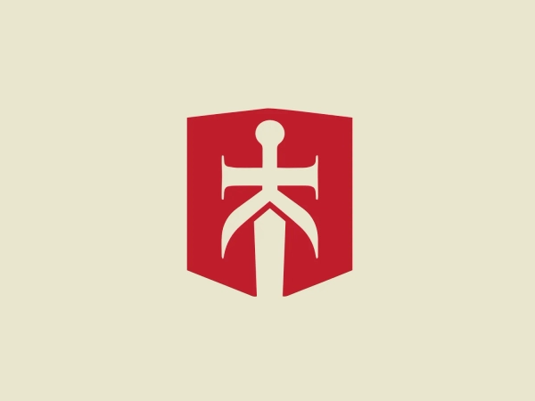 The Burny Kaliburn logo features a bold, solid red shield as its backdrop, with a white stylized emblem at its center that resembles an abstract figure or perhaps an anchor, with arms extending upward and outward and a split bottom section that spreads into a broad, stable base. The design has a strong and protective connotation, with its shield shape suggesting defense or safety, and the emblem inside conveying strength and stability. The colors are high-contrast, which allows for the icon to stand out with clarity and direct visual impact.