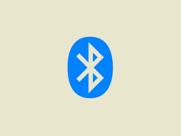 The Bluetooth logo features a stylized white Bluetooth symbol centered within a bright blue oval. The Bluetooth icon itself consists of a pointed line shape and two angular chevrons interlocked, creating a symmetric and abstract representation of the letter 'B'. The blue oval has no border and its edges are smooth, creating a simple yet bold contrast against the white icon. The logo exudes a modern and clean aesthetic with its minimalist design and vibrant color, which would stand out well against a complementary background.