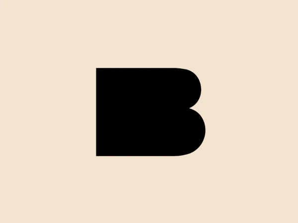 The image depicts a simple, bold logo consisting of a black letter 'B'. This letter has a modern, sans-serif typeface with clean lines and curved corners, giving it a streamlined, contemporary look. The BuildBuddy logo has a solid, monochromatic color scheme that creates a stark contrast and ensures high visibility. The overall design aesthetic is minimalist and would lend itself well to versatile branding applications due to its clear and striking appearance.