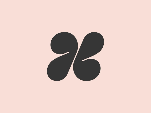 The logo presented for Hazel is a modern, abstract design comprising two mirrored elements that resemble stylized droplets or commas, creating a dynamic sense of motion and symmetry. The color of the logo is a solid, warm terracotta or rusty red, which conveys a sense of earthiness and vitality. The shapes are smooth and organic with gently curving lines and rounded terminations that convey a friendly and approachable aesthetic. The overall design is minimalistic and could symbolize connectivity, unity, or an abstract representation of natural elements.