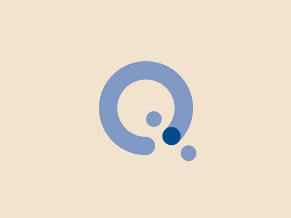 The image displays a minimalistic logo that is built around a stylized letter "Q." The logo features a large, pastel blue "Q" with its tail curving inward, ending with a flourish that includes two smaller circles in a darker shade of blue, creating a gradient effect. The overall design aesthetic is modern and clean, with a sense of fluidity and motion implied by the curving lines and descending circles. This simplicity and the cool color palette suggest a professional and contemporary brand identity for Quantum Technologies Programme.