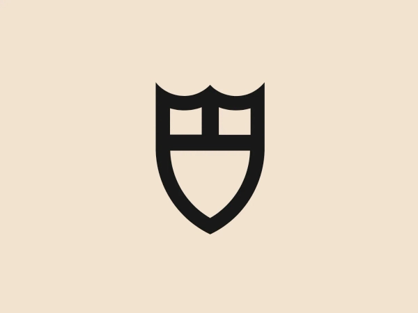 The Tudor logo features a stylized red shield with a flat top and rounded bottom. Inside the shield, there are four squares arranged in a two-by-two grid, creating a sense of unity and structure. The design is minimalistic and modern, with a bold monochromatic color scheme conveying a strong and protective feel. The squares may represent windows or blocks, indicating organization, structure, or a foundational element.