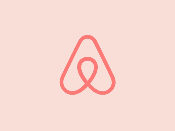 The Airbnb logo is a stylized "A," featuring a continuous line that forms an upside-down teardrop shape and a loop resembling an infinity symbol. The design is modern, simplistic, and conveys a sense of fluidity and continuity. The soft, salmon pink color offers a warm and inviting feeling.