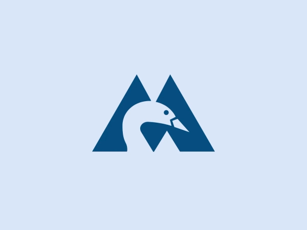 The Montshire Museum of Science logo is a stylized representation of what appears to be a mountain shape with a bird integrated into the design. There are two overlapping triangles forming the mountain, and a negative space within the right triangle depicts a bird in flight, with its wings angling upwards, giving an impression of ascent or progress. The design utilizes a single dark blue color, which adds to the professional and clean look. The use of negative space to create the bird is clever, merging the themes of nature and freedom.